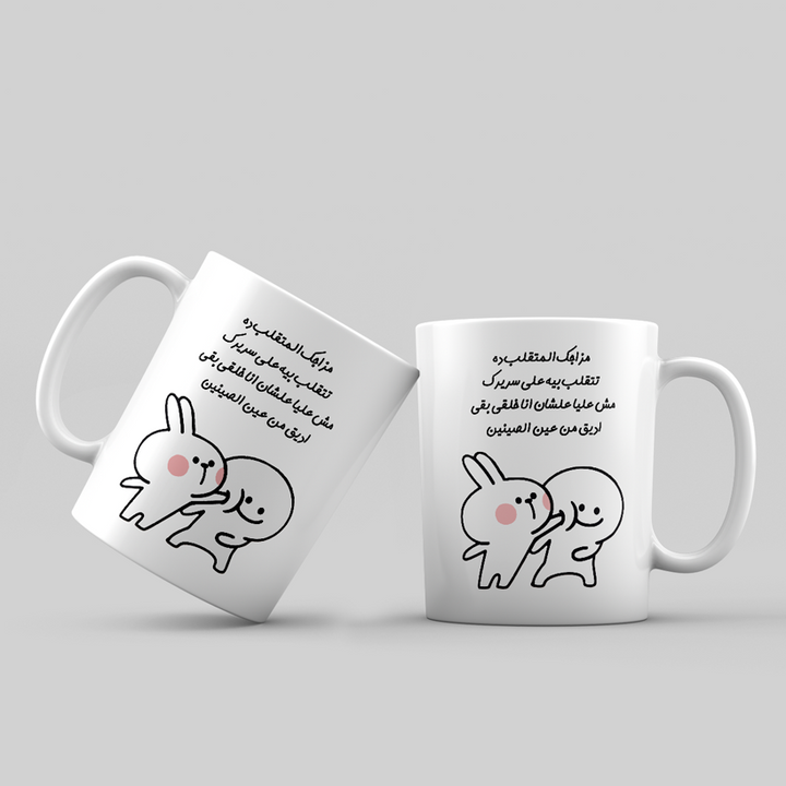 Two white mugs with cartoon rabbits and Arabic text on a light gray background